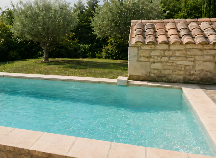 Pool house en enduit imitation pierre au bord d’une piscine, oliviers et jardin méditerranéen